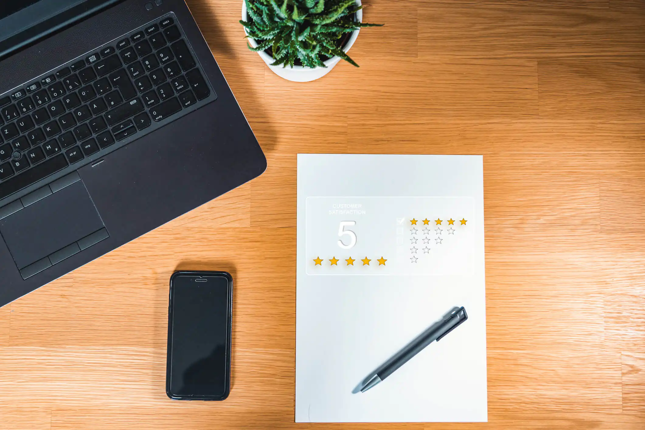 laptop, mobile phone and note with the 5 star reviews on the table
